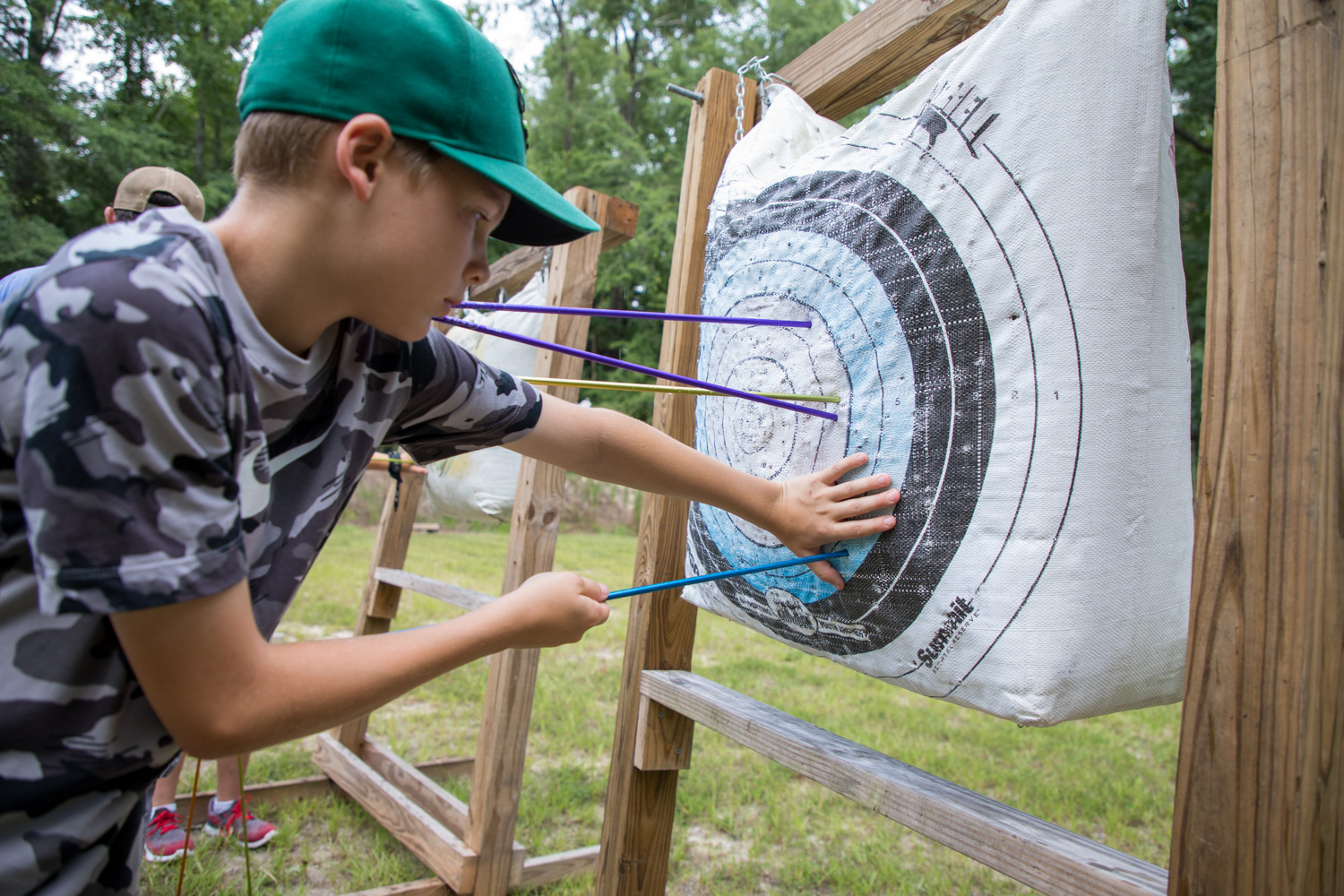 youth pulling arrows from a bag archery target