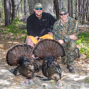 wheelin' sportsmen event participant and mentor posing with two harvested turkeys