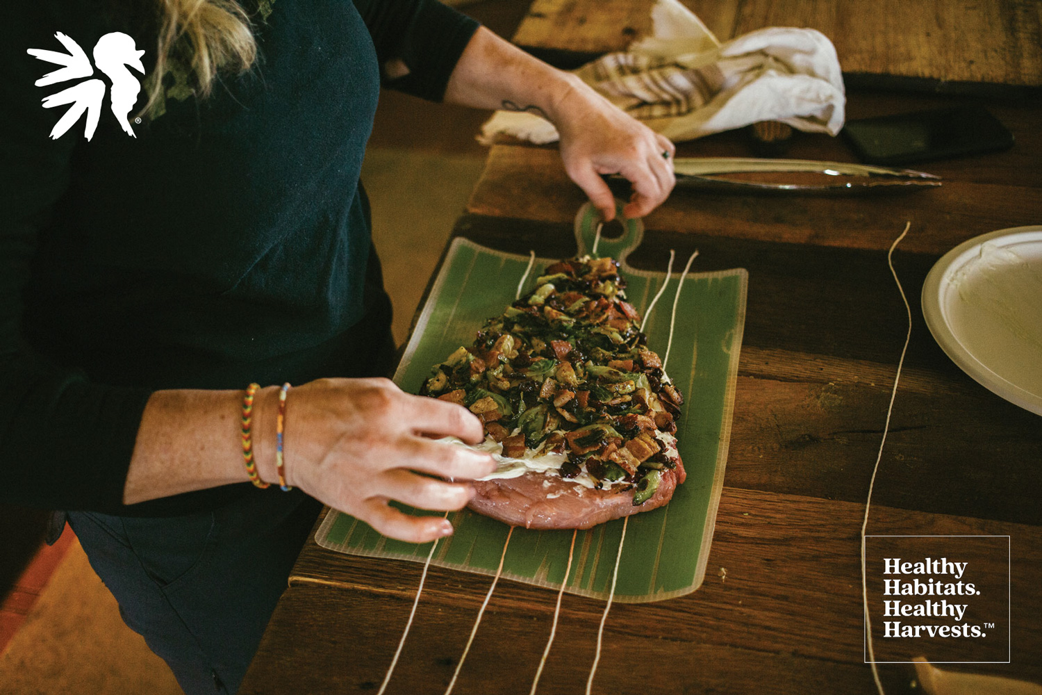 woman preparing wild turkey breast stuffed with bacon, cranberries and brussel sprouts