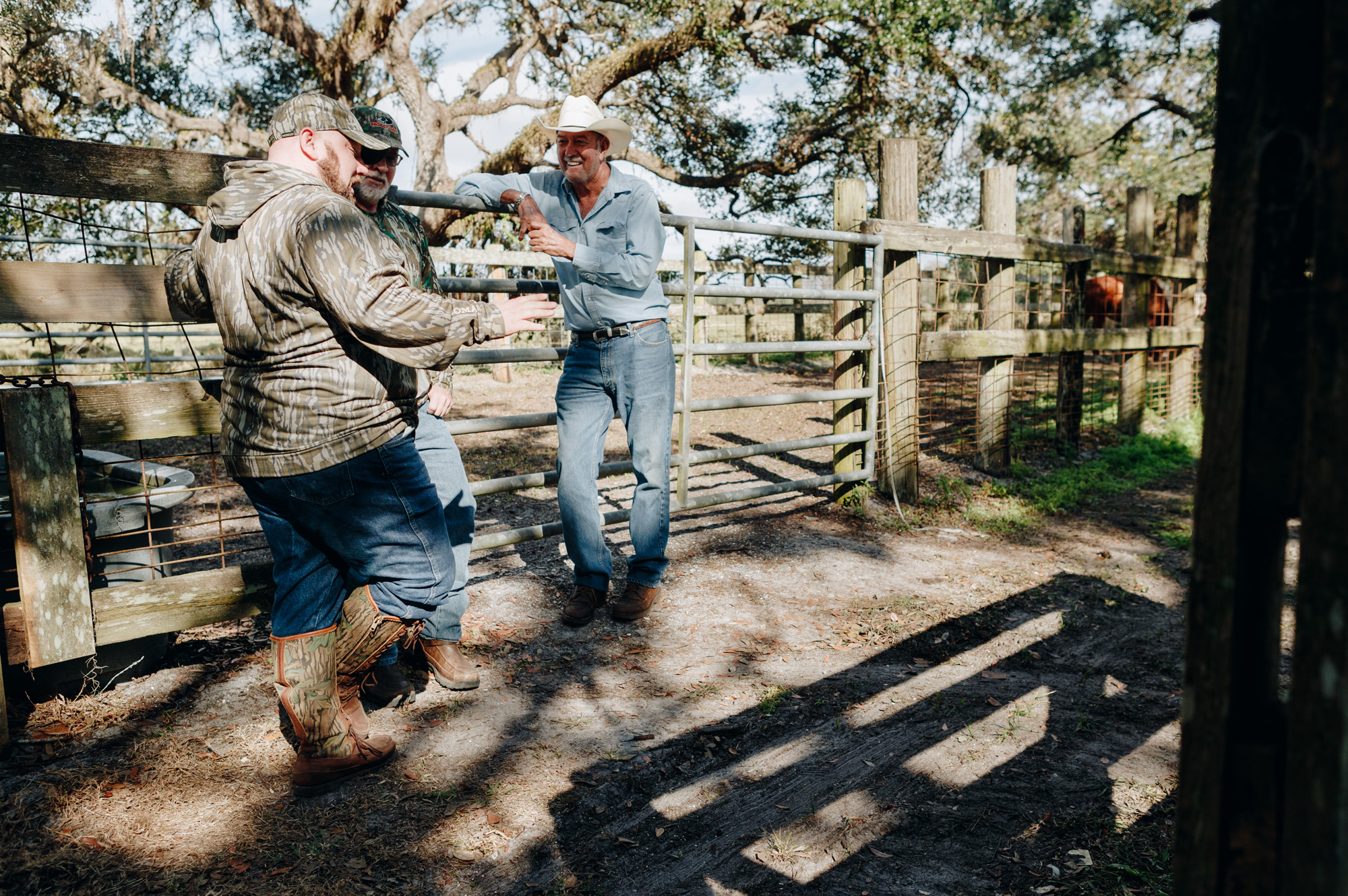rancher and two hunters talking at a fence gate in florida