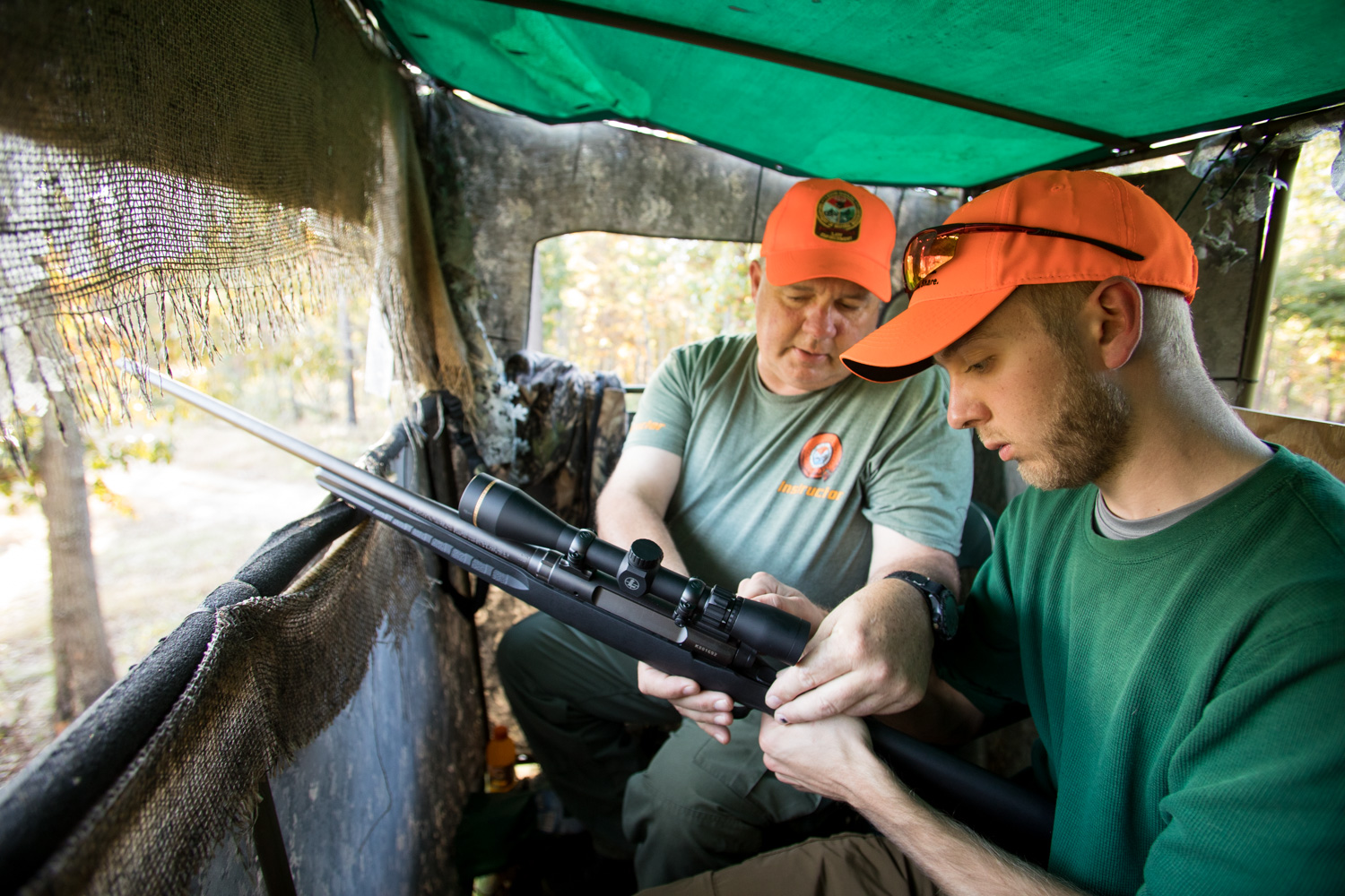 mentor showing a new hunter how to use a rifle