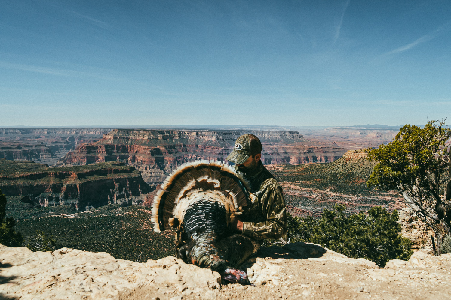 hunter posing with a turkey with the grand canyon in the background
