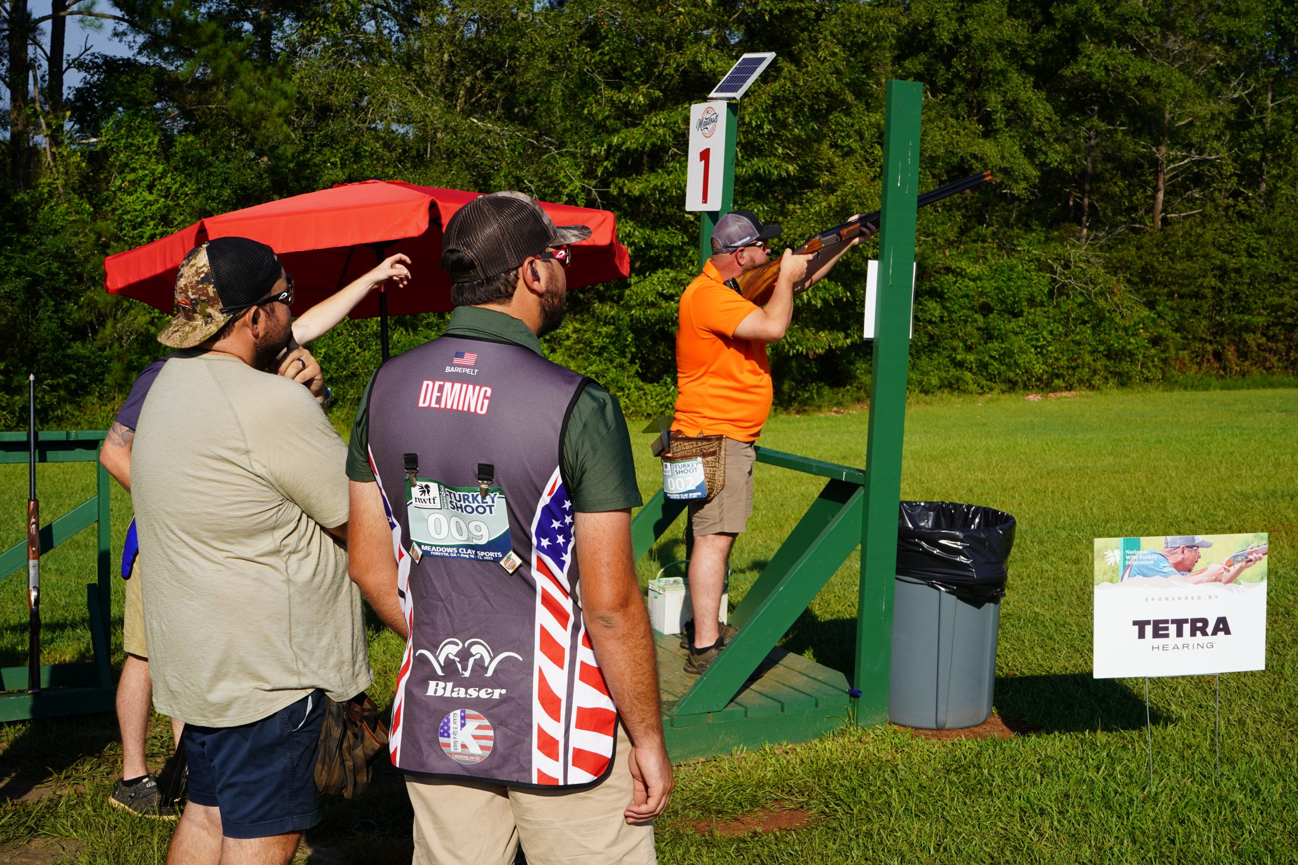 group of competitors watch the shooter in the shooting station take aim on targets during the 2023 Turkey Shoot.