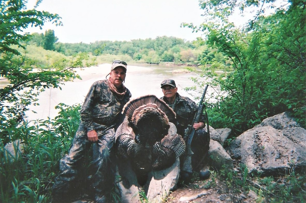 Two hunters with a turkey by a river