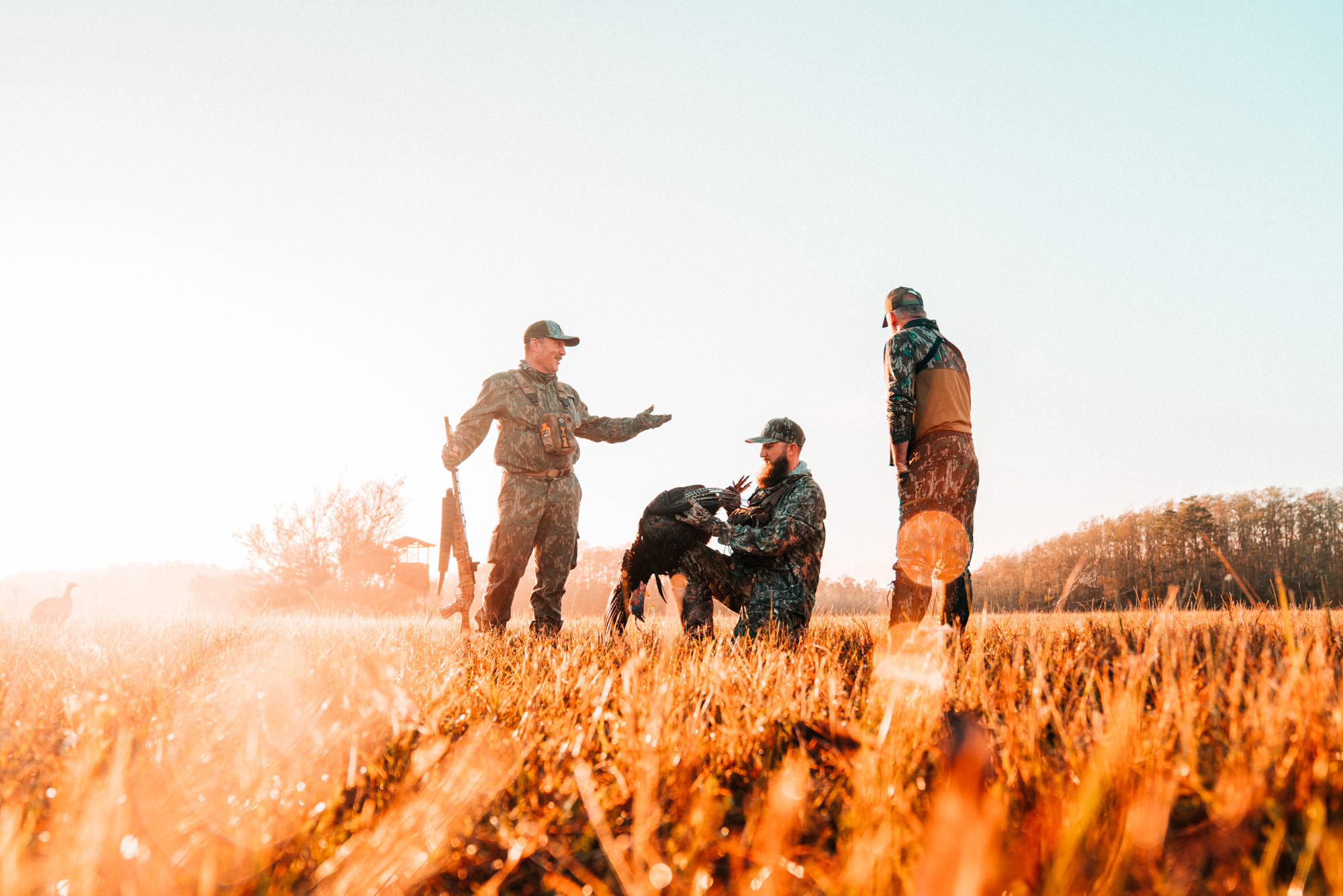 three hunters in a field with a turkey