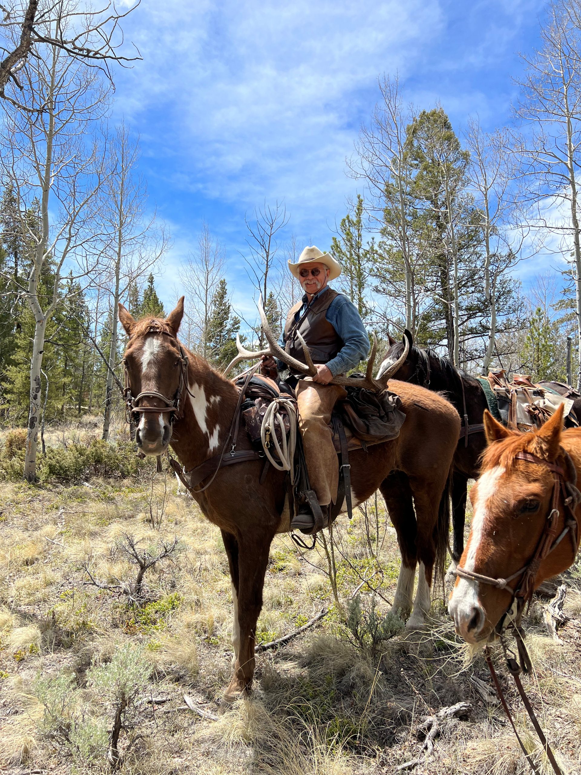 Spezee holding an elk antler on horseback