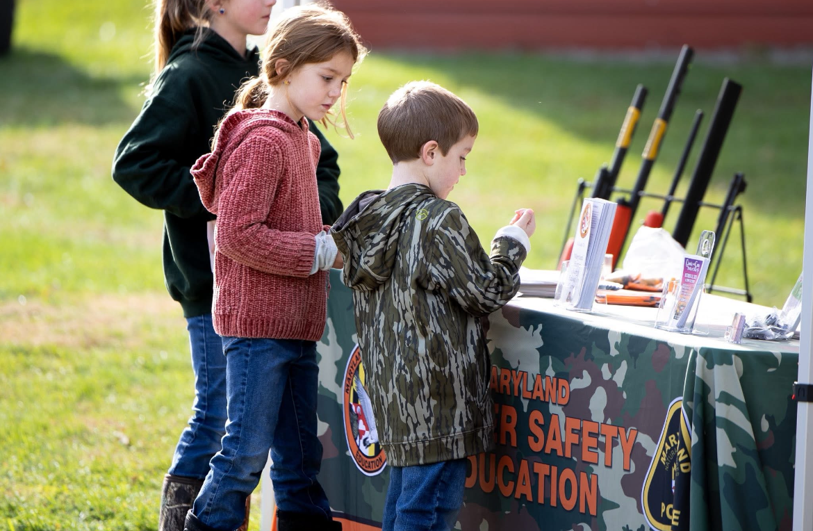 Two young kids at hunting safety table.