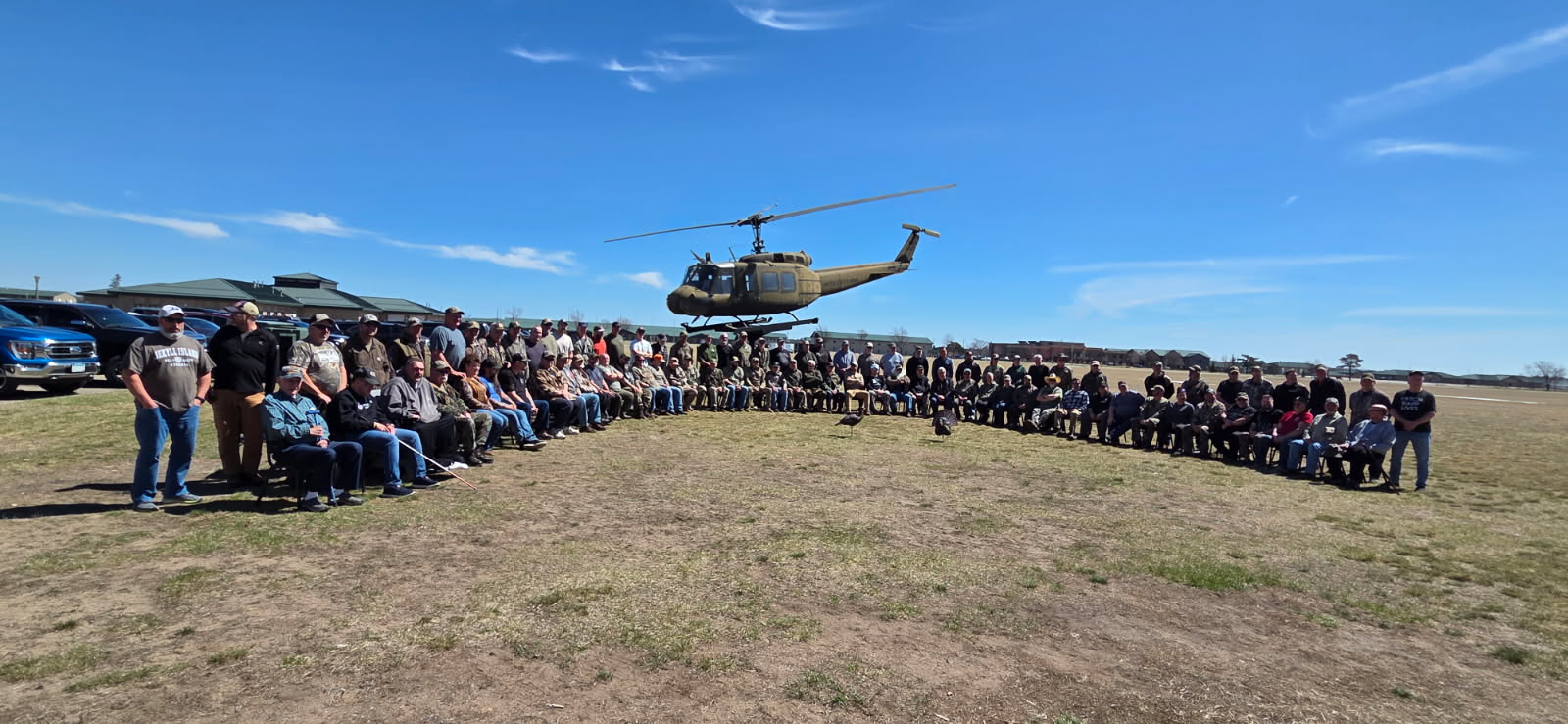 Veterans and volunteers pose in front of a helicopter